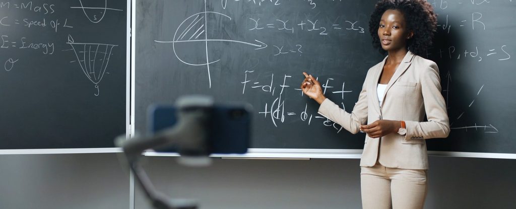 A professor teaching about equations in front of a smartphone -- in order to reach remote learners