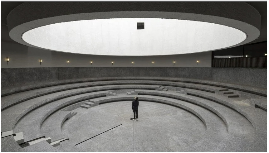 A man stands beneath a massize circular opening in one of the Dezeen Award winners for 2021